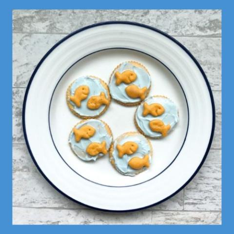 Image of small Goldfish crackers on pale blue tinted cream cheese on round crackers.