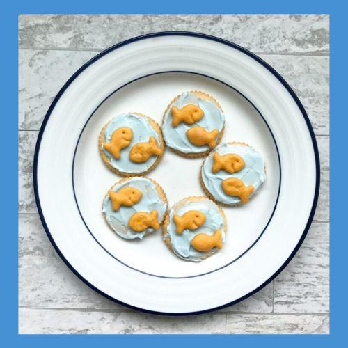 Image of small Goldfish crackers on pale blue tinted cream cheese on round crackers.
